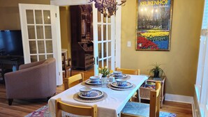 Un'area pranzo con un tavolo apparecchiato per quattro persone, un lampadario e un quadro appeso al muro.