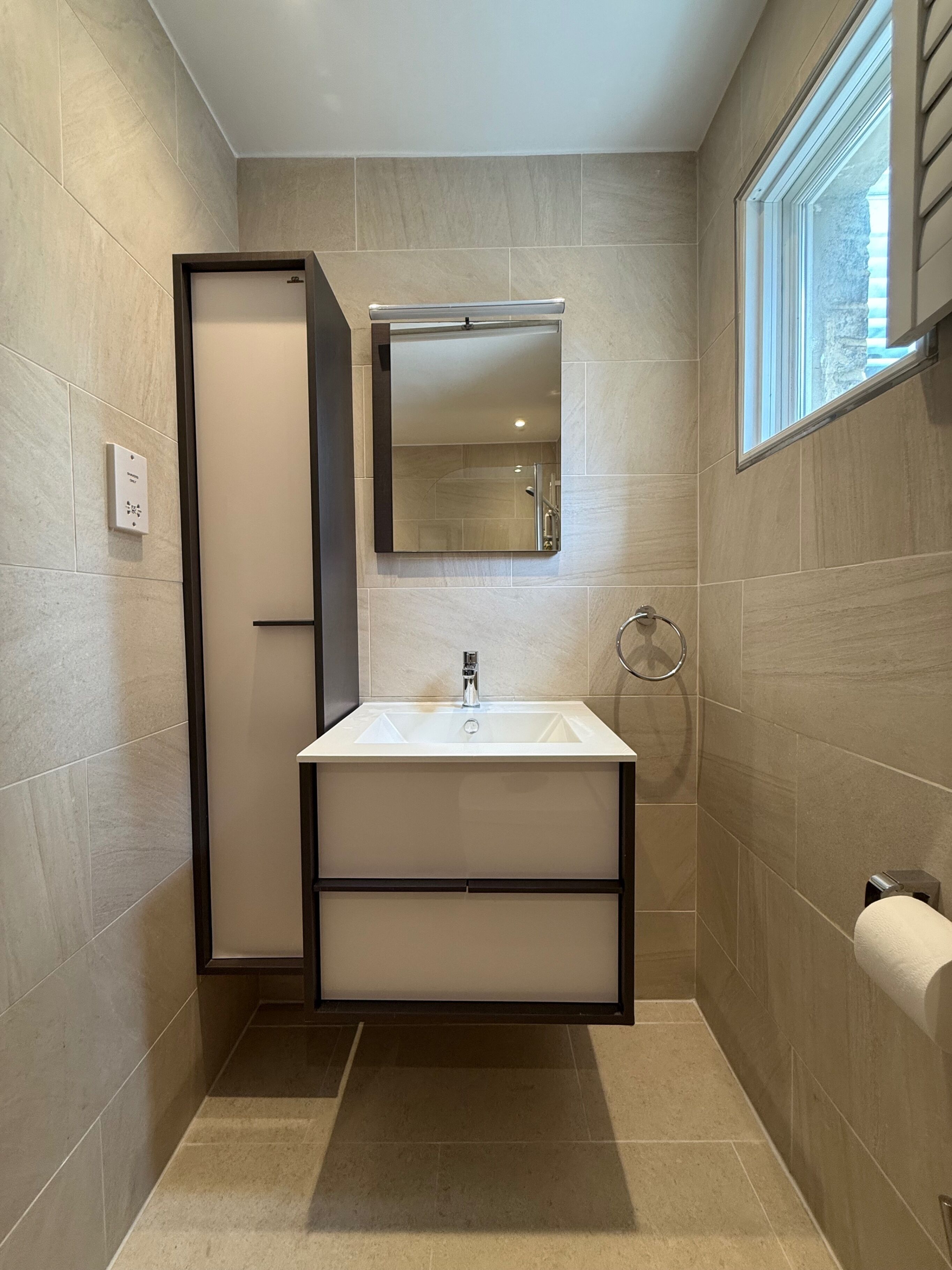 A modern bathroom with a white sink, a mirror, and a towel rack.