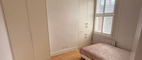 A bedroom with a bed, wardrobe, and window.