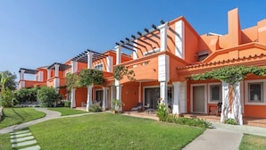 A row of orange buildings with white columns, a well-maintained lawn, and a clear sky.