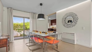 A modern dining area with a table set for four, clear glass chairs, a pendant light, and a decorative wall mirror.