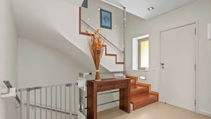 A modern staircase with a glass railing, a wooden desk, and a door.