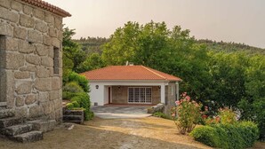 A stone building with a red-tiled roof, a paved pathway leading to a door, and lush greenery surrounding the property. - Quiet Escape by the River w/ Pool by HostWise (Tábua)