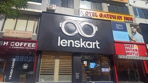 A building with multiple businesses including a hotel, a coffee shop, and an eyewear store. - HOTEL GATEWAY INN (Ahmedabad)