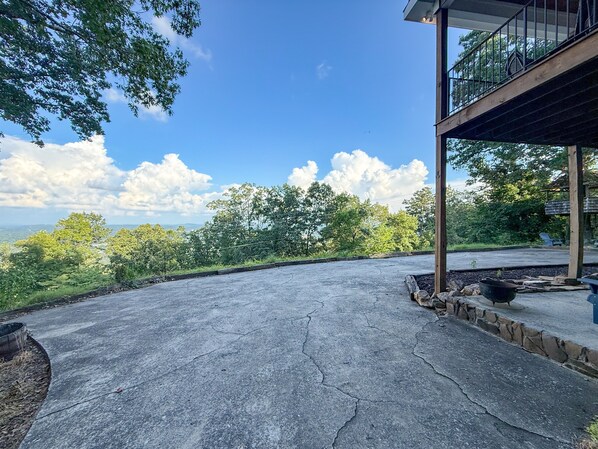 A spacious outdoor area with a concrete floor, surrounded by trees and a clear sky.