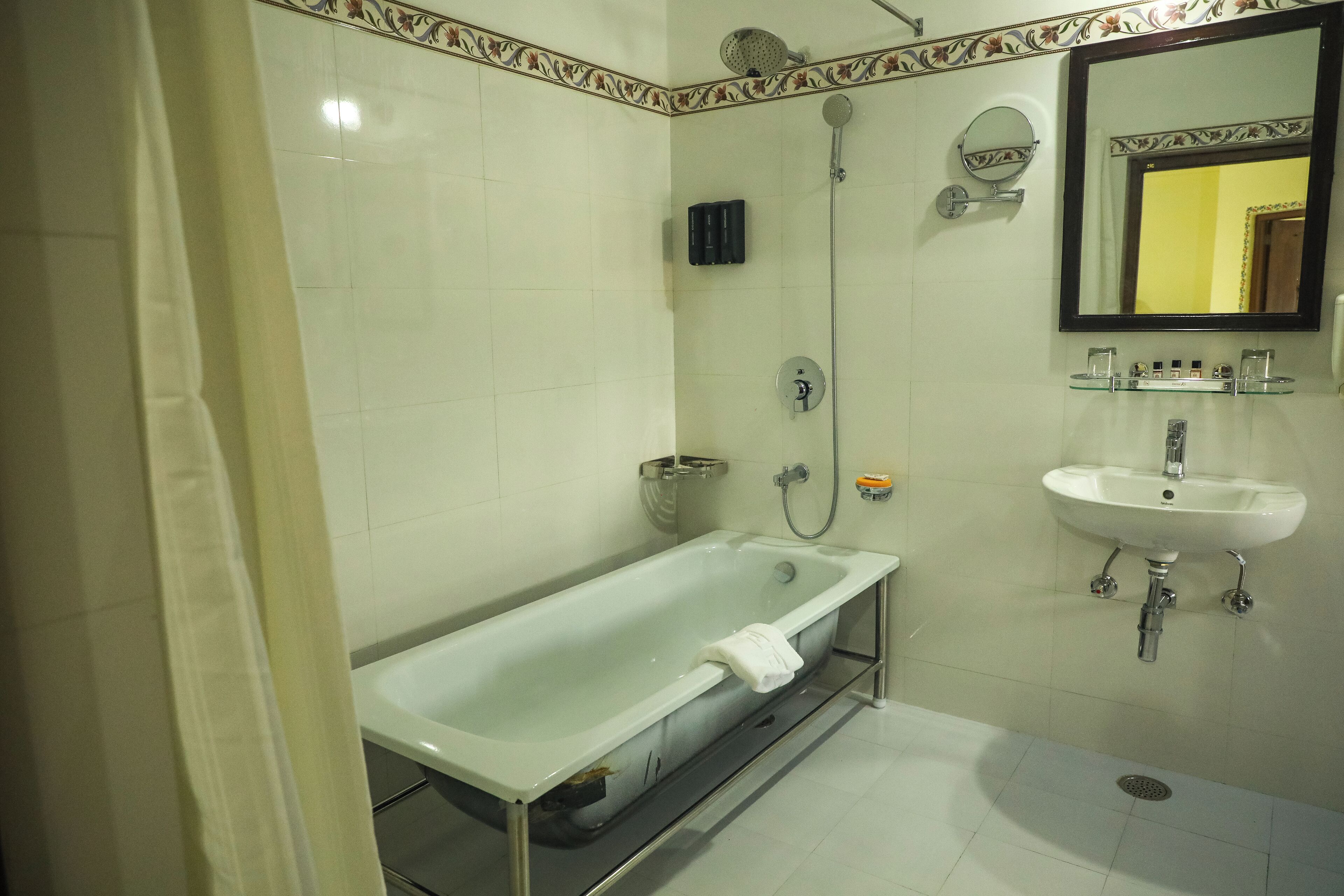 A bathroom with a glass-enclosed bathtub, a wall-mounted sink, and a shower.
