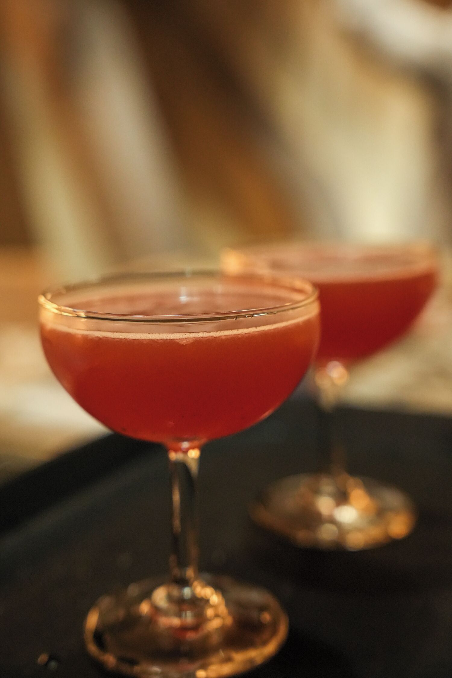 Two cocktail glasses on a dark surface.