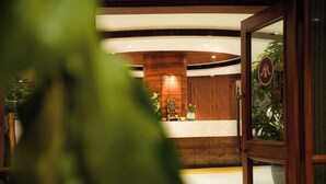 A reception area with a wooden reception desk, a large pillar, and a sign indicating a wheelchair-accessible entrance. - Hotel Menaka Inn Dharwad (Dharwad)