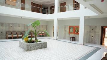 A spacious atrium with a central planter, multiple seating areas, and artwork on the walls.