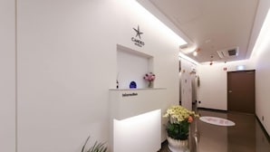 Zona de recepción de hotel con diseño moderno, que incluye mostrador de recepción, punto de información y señalización del hotel.
