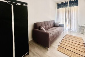 A modern living room with a brown sofa, a black wardrobe, and a wooden rug. - Le Conchiglie Di Grace - Apartment with Balcony, Alassio, Italy (Alassio)