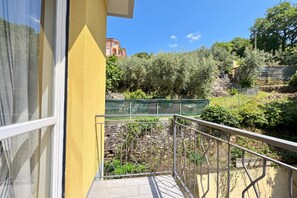 A balcony with a stone wall and metal railing overlooking a garden with olive trees and a stone pathway. - Le Conchiglie Di Grace - Apartment with Balcony, Alassio, Italy (Alassio)