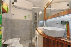 Casa de banho moderna com uma grande pia, cabine de chuveiro em vidro e toucador de madeira.