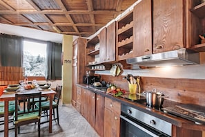 Una cocina con armarios de madera, una estufa y un comedor con mesa y sillas.