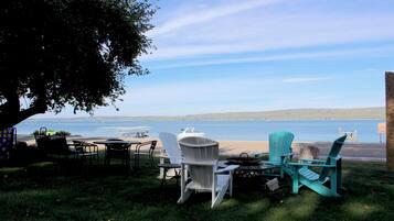 An outdoor seating area with chairs and tables, overlooking a body of water and distant hills.