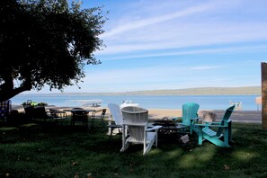 An outdoor seating area with chairs and tables, overlooking a body of water and distant hills.
