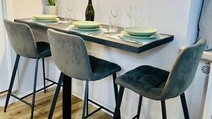 A dining area with a long table, four grey upholstered chairs, and a potted plant. - Residence at Passetto historic center (Verona)