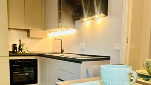 A compact kitchen with a built-in oven, a sink, and a dining area with a table and chairs. - Residence at Passetto historic center (Verona)