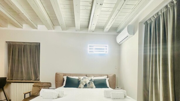 A modern hotel room with a large bed, a desk, and a window with curtains. - Residence at Passetto historic center (Verona)