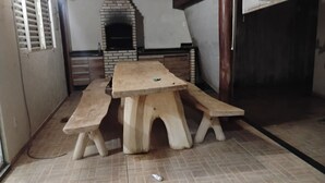 A wooden table with benches in a room with a tiled floor and a brick fireplace.