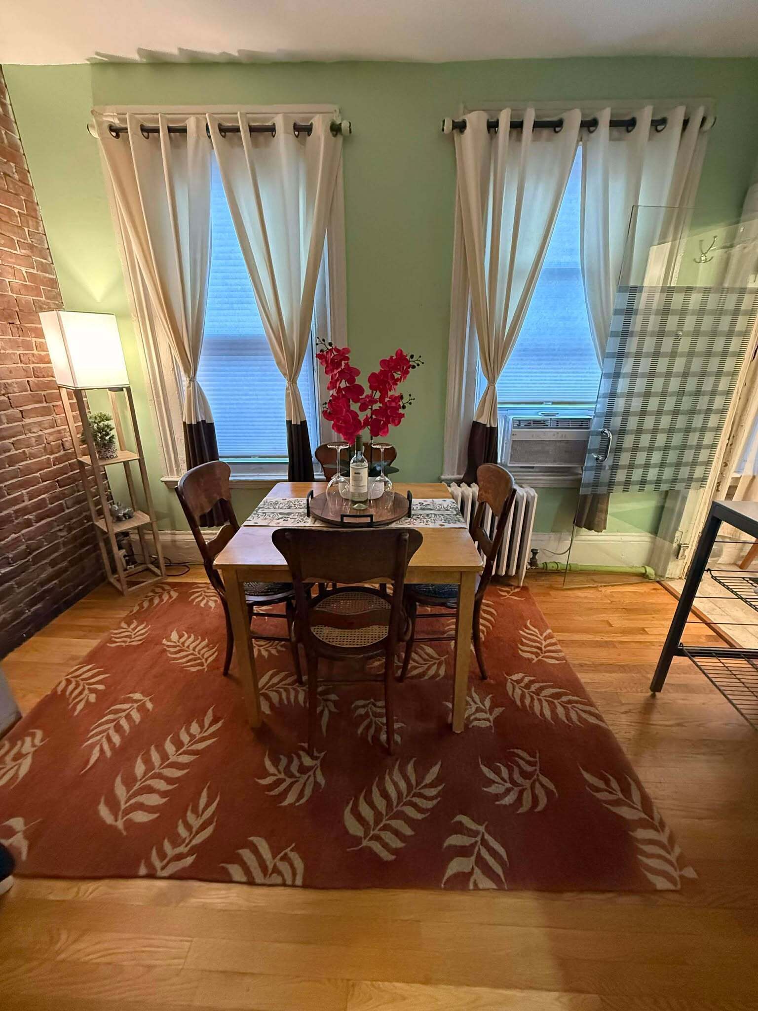 A dining area with a table, chairs, a vase with flowers, and a radiator.