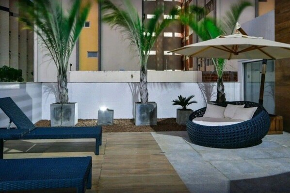 An outdoor lounge area with lounge chairs, a round seating area, and potted plants.