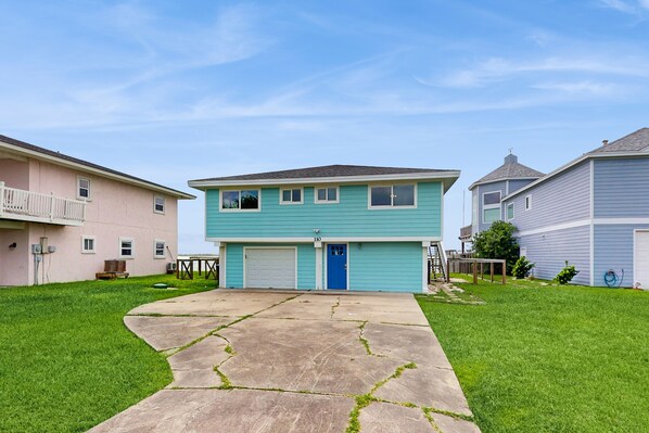 A two-story residential building with a blue exterior, a front garage, and a well-maintained lawn.