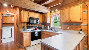 Una cocina con armarios de madera, microondas, estufa y lavaplatos.