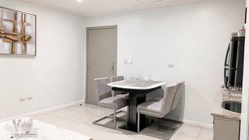 A modern kitchen with a built-in oven, a dining area with a round table and grey chairs, and a white marble table.