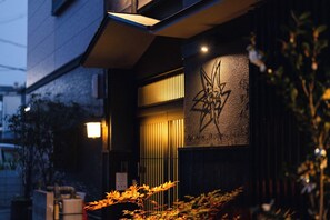 Facciata di un edificio con esterno scuro, una striscia luminosa verticale e un elemento decorativo a parete.