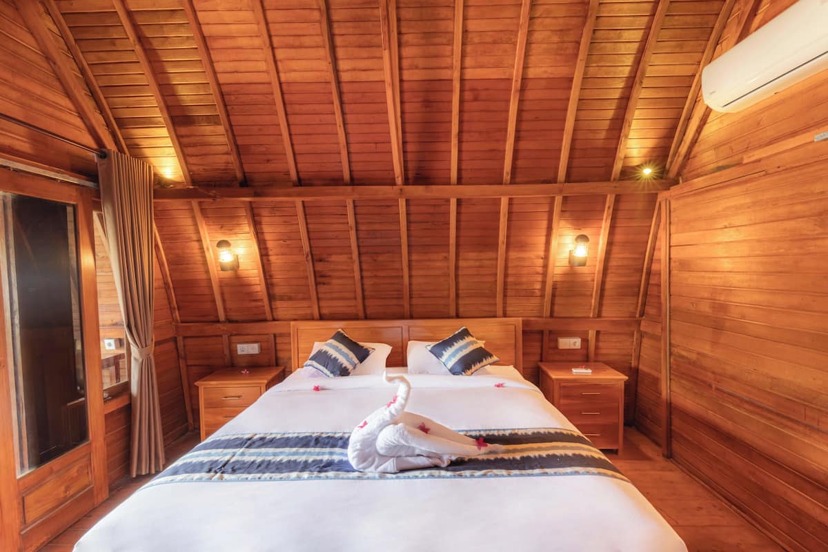 Dormitorio de cabaña de madera con cama, mesitas de noche y una toalla con forma de cisne.