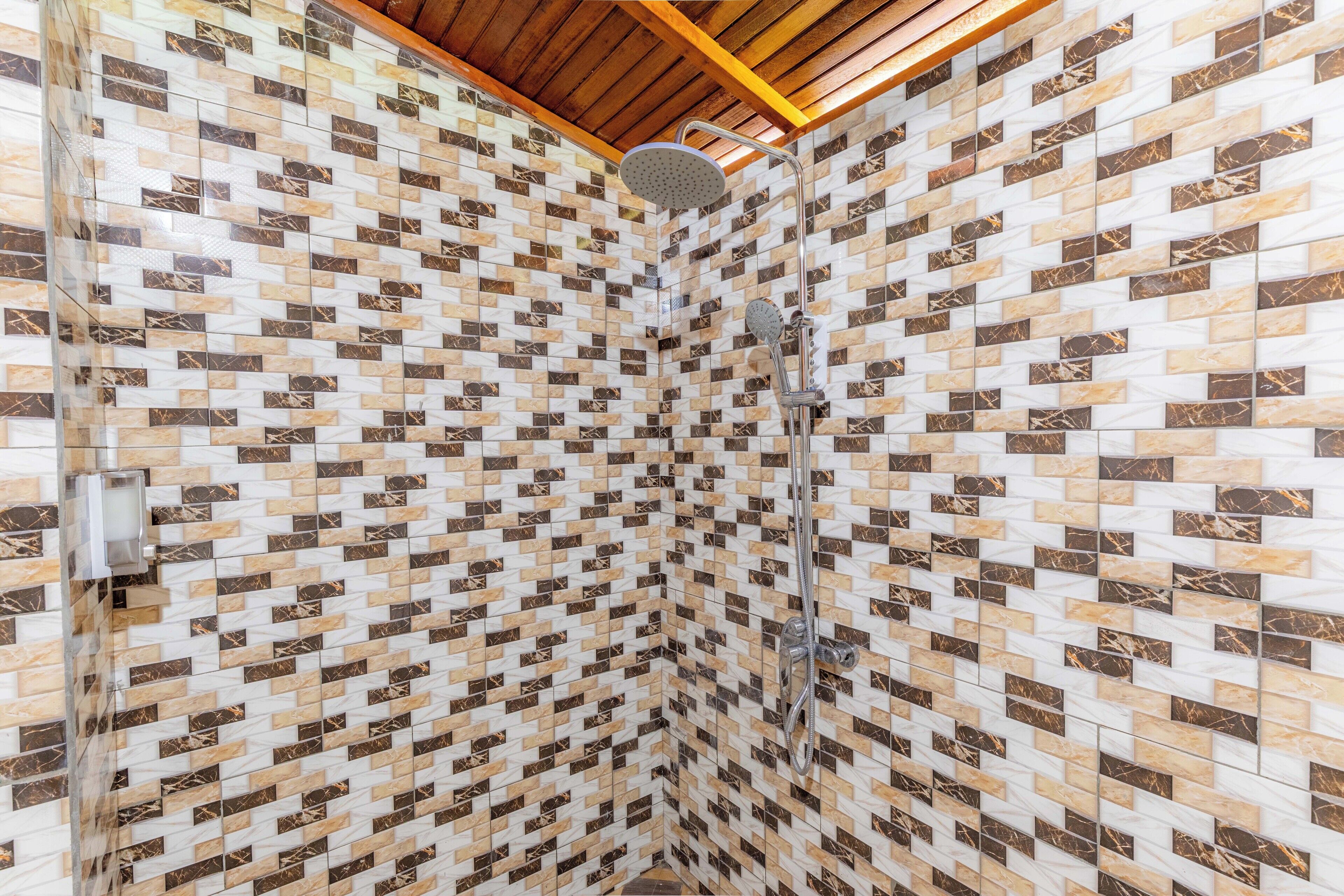Une douche avec un mur recouvert de carreaux à motifs et un plafond en bois.