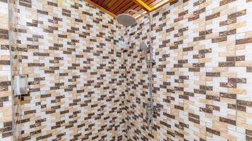 Une douche avec un mur recouvert de carreaux à motifs et un plafond en bois.