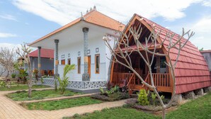 A two-story building with a tiled roof, a balcony, and a garden area with pathways and plants. - The Gili Menjangan (Pejarakan)
