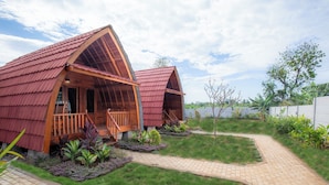 Two wooden cabins with red roofs and wooden balconies, surrounded by a well-maintained garden and a paved walkway. - The Gili Menjangan (Pejarakan)
