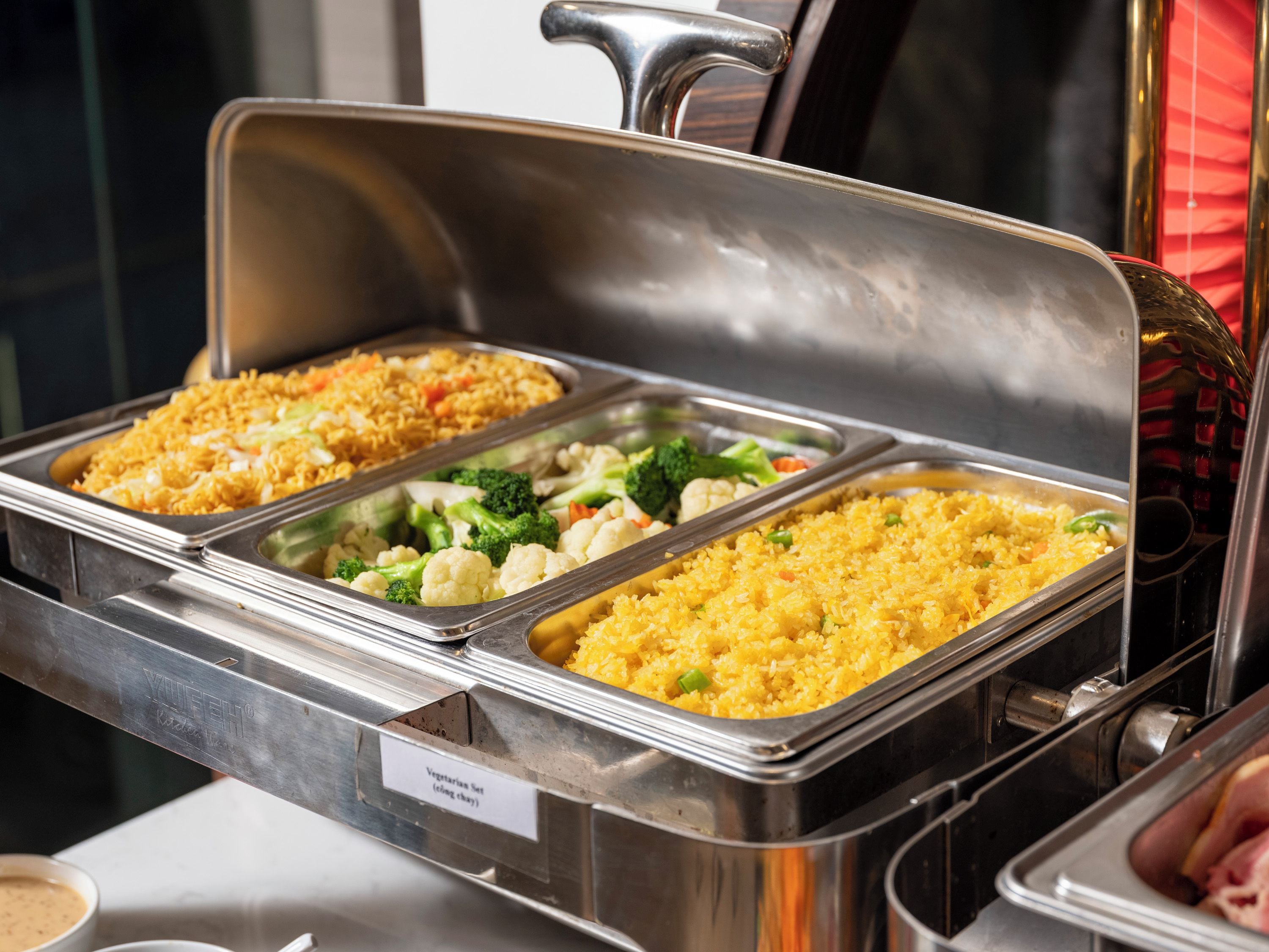 A buffet with multiple food trays, including rice dishes and vegetables.