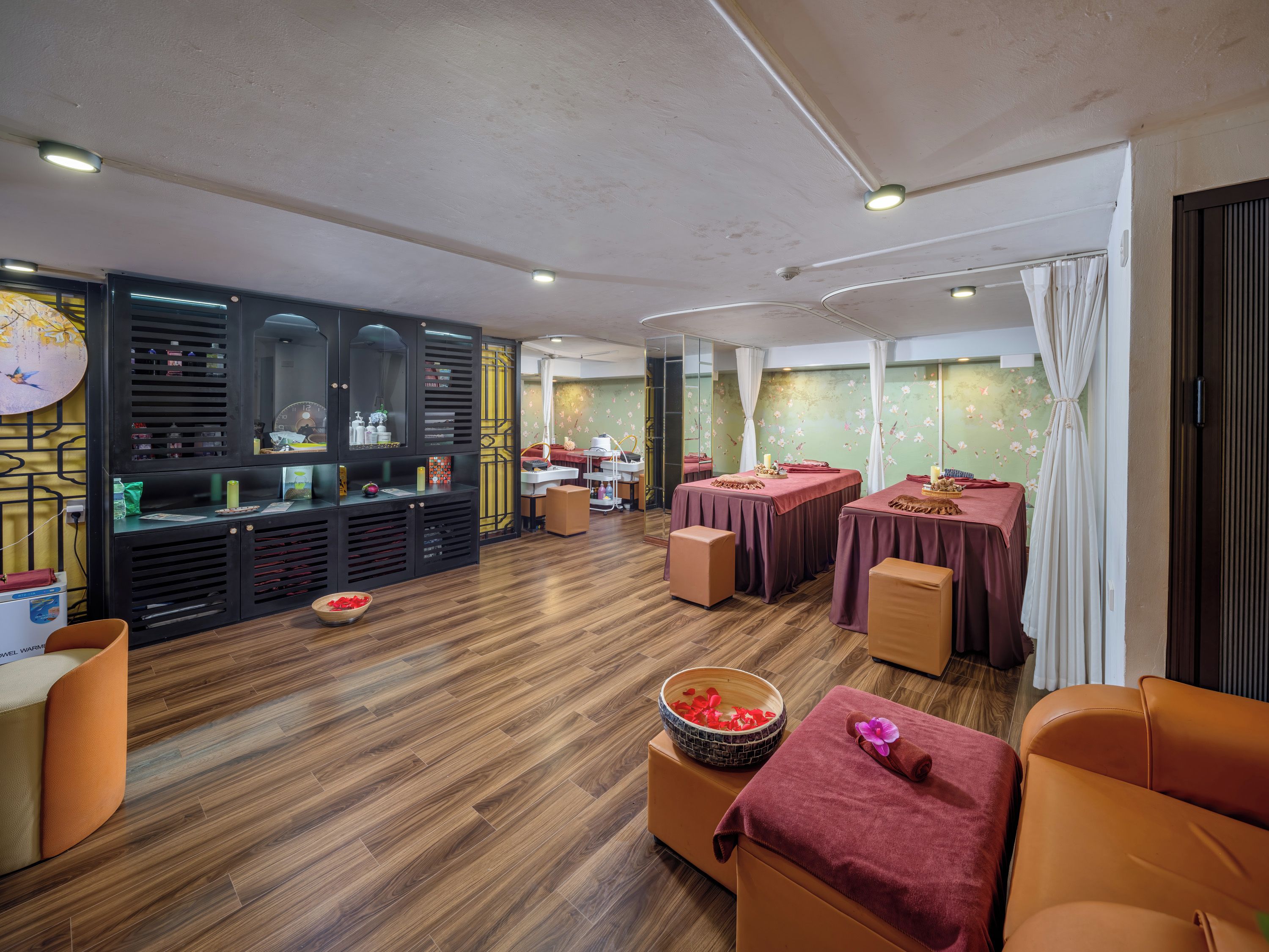 Een wellnessruimte met houten vloeren, een receptiebalie en een ruimte voor massages.