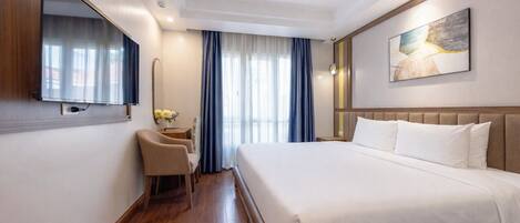 Habitación de hotel con una cama grande, un escritorio con silla, un espejo y un cuadro en la pared.