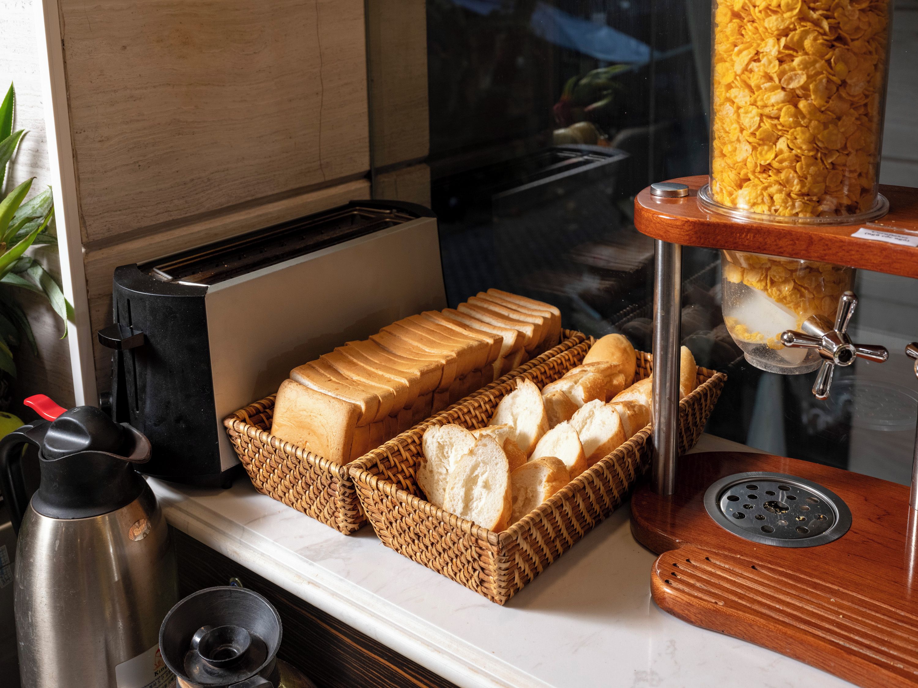 A breakfast setup with a toaster, bread baskets, and a cereal dispenser.