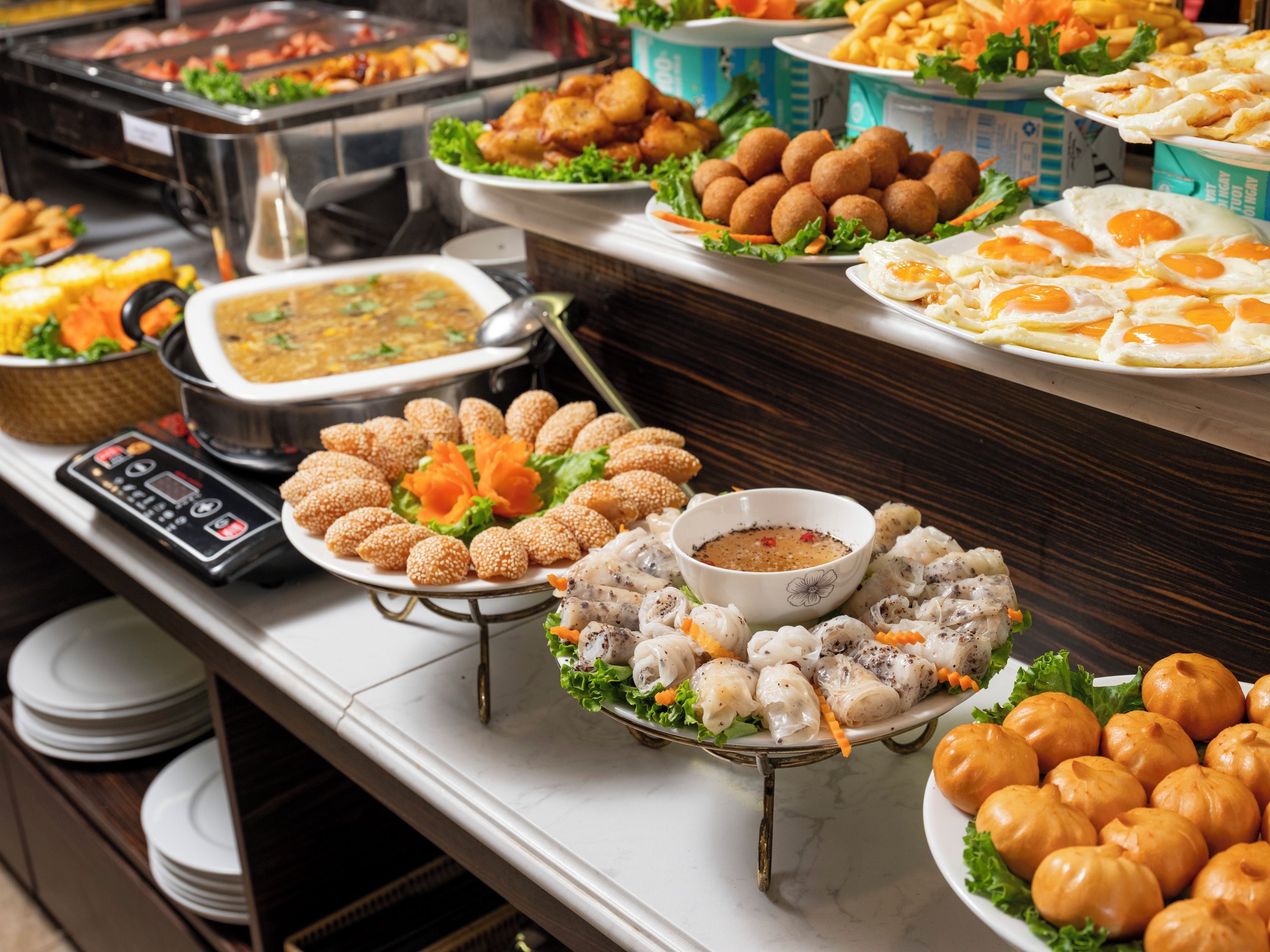 A buffet with various dishes including fried items, eggs, and a bowl of soup.