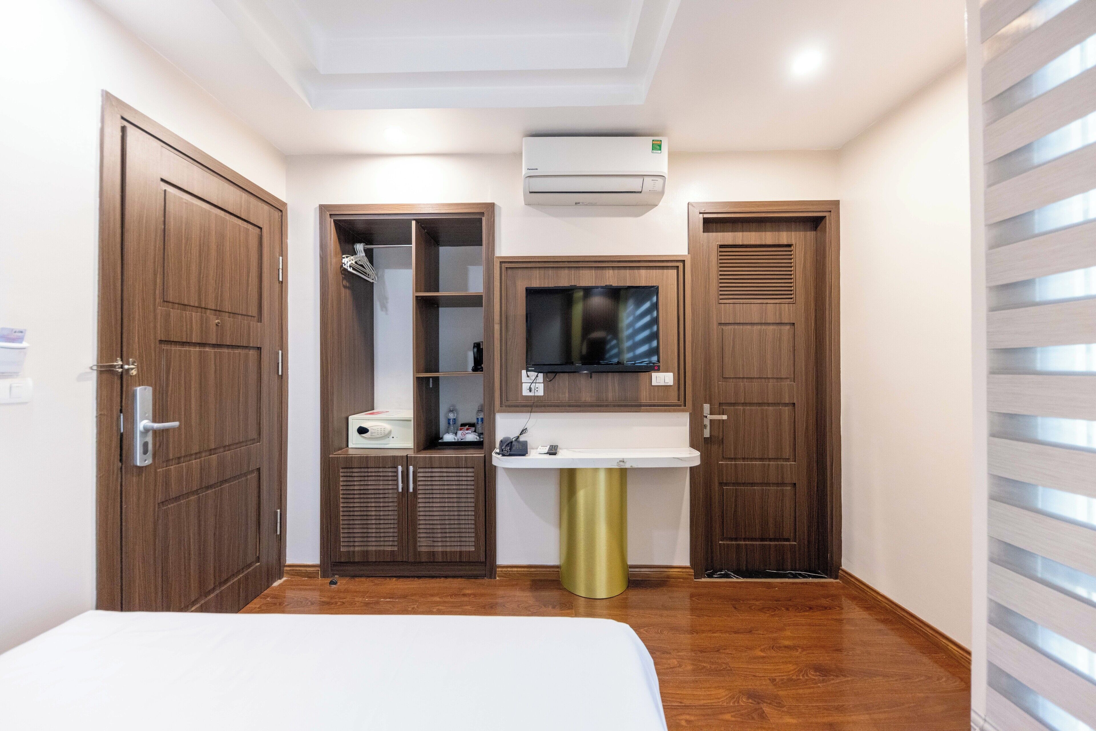 A hotel room with a bed, a TV, a sink, and wooden wardrobes.