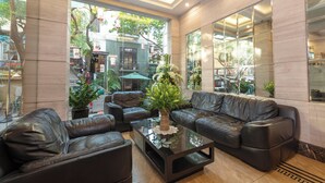 Un hall con sofás de cuero, una mesa de centro de vidrio y plantas en macetas.