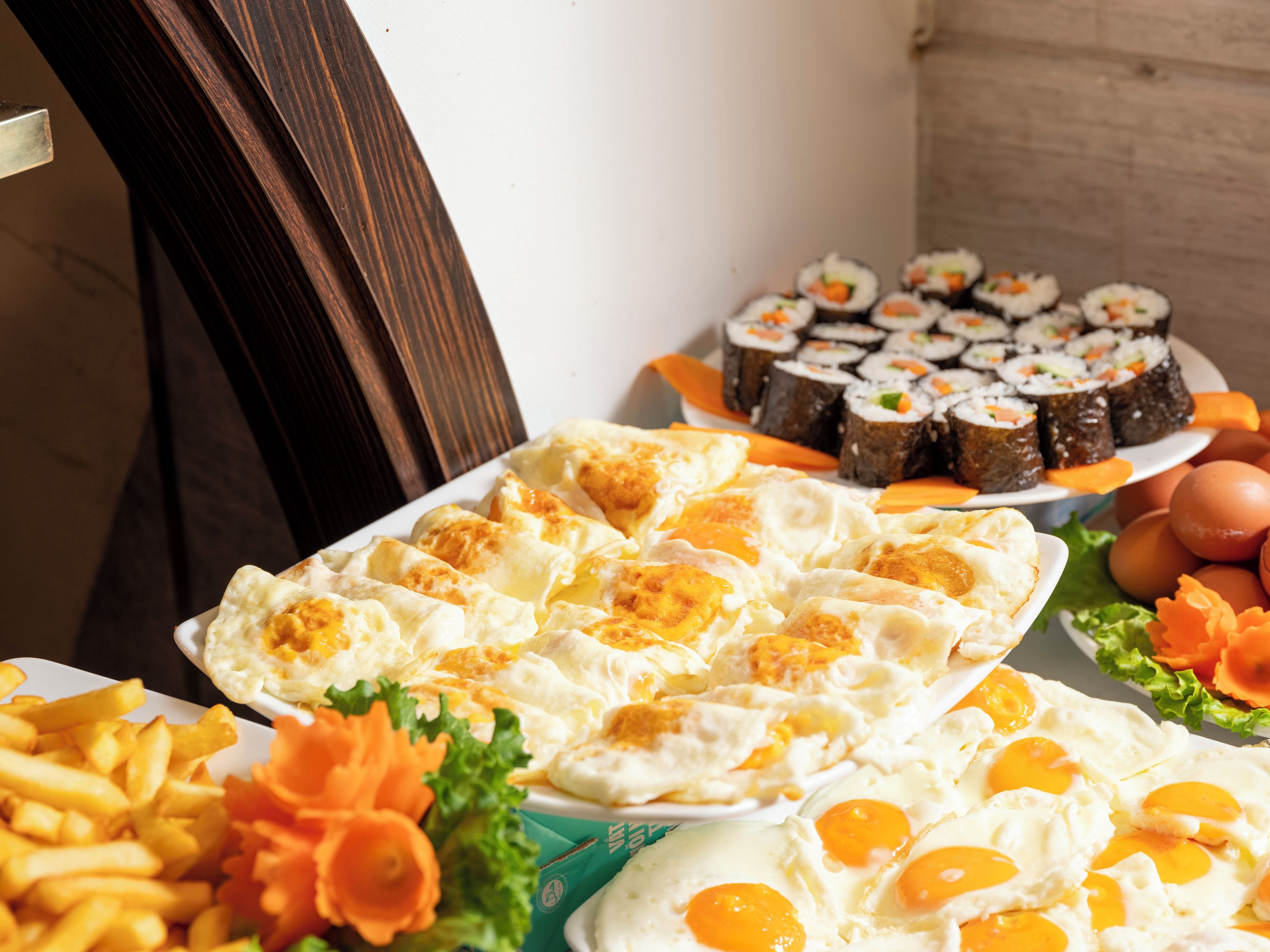 Buffet com diversos alimentos, incluindo ovos, batatas fritas e sushi.