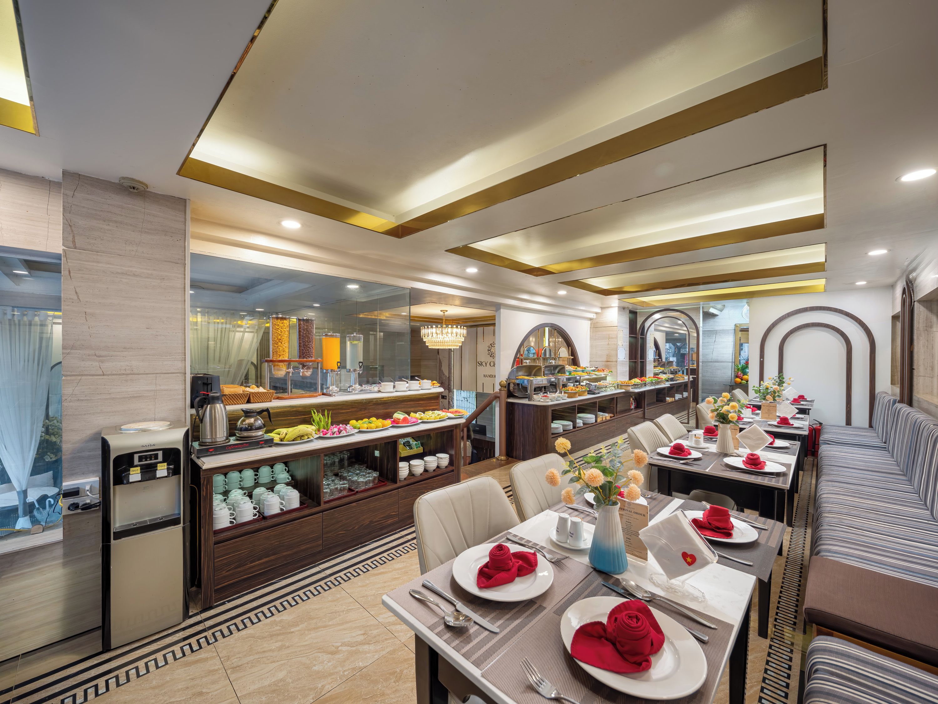 Hotellets spiseområde med buffet, siddepladser og udsigt til køkkenet.