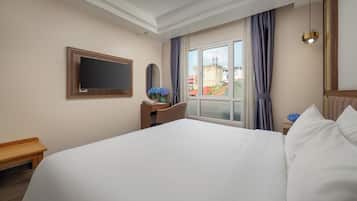A hotel room with a large bed, a desk, a chair, a television, and a window with curtains.