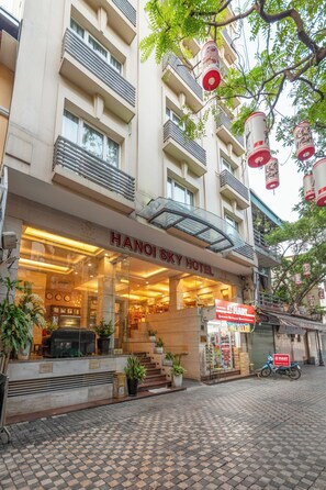 Hotel Hanoi Sky met een glazen gevel, een terras en zicht op een E-Mart winkel.