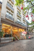 The Hanoi Sky Hotel with a glass facade, outdoor seating area, and a visible E-Mart store.