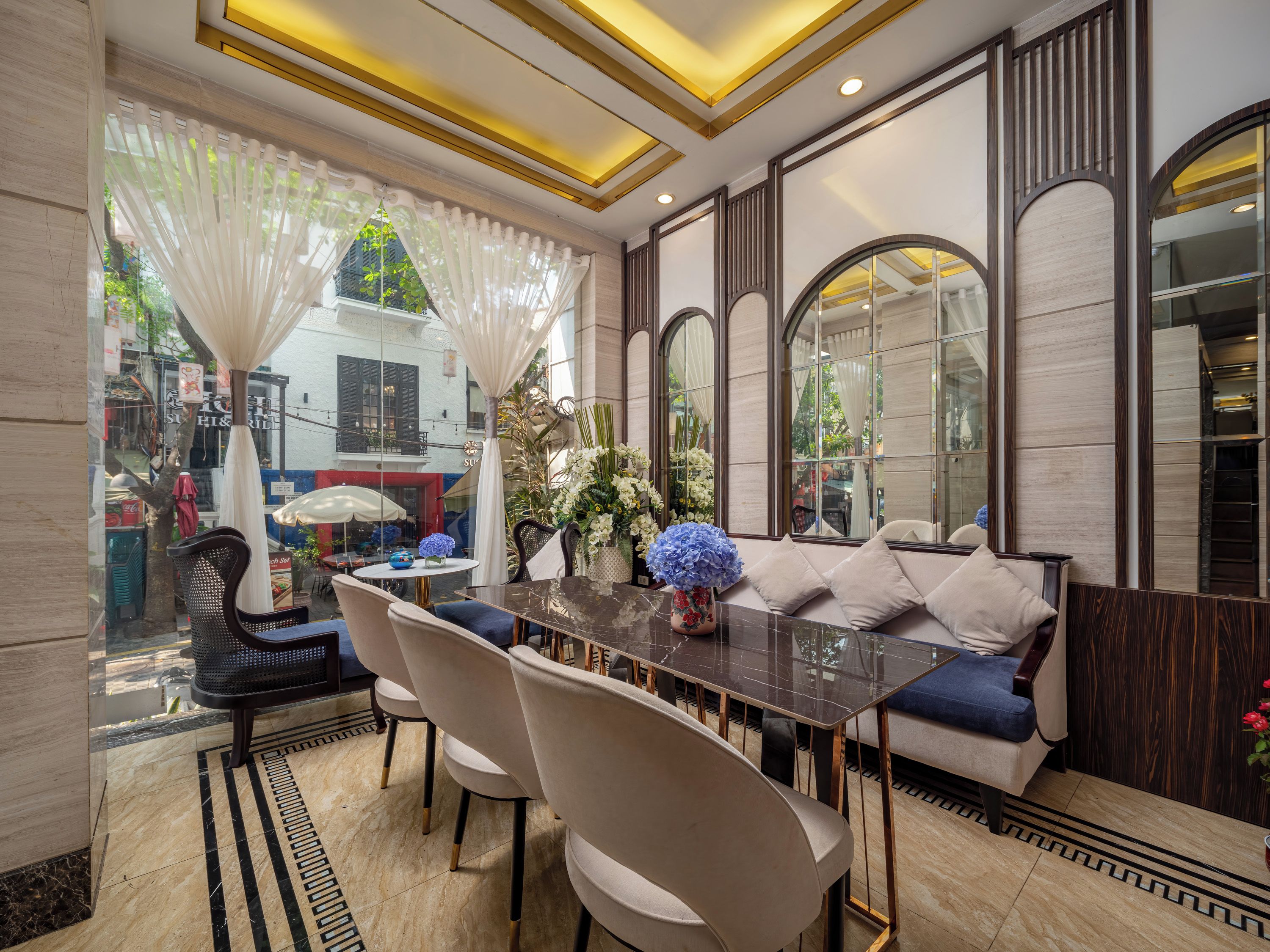 A dining area with a marble floor, a round table with chairs, and a sofa with cushions.