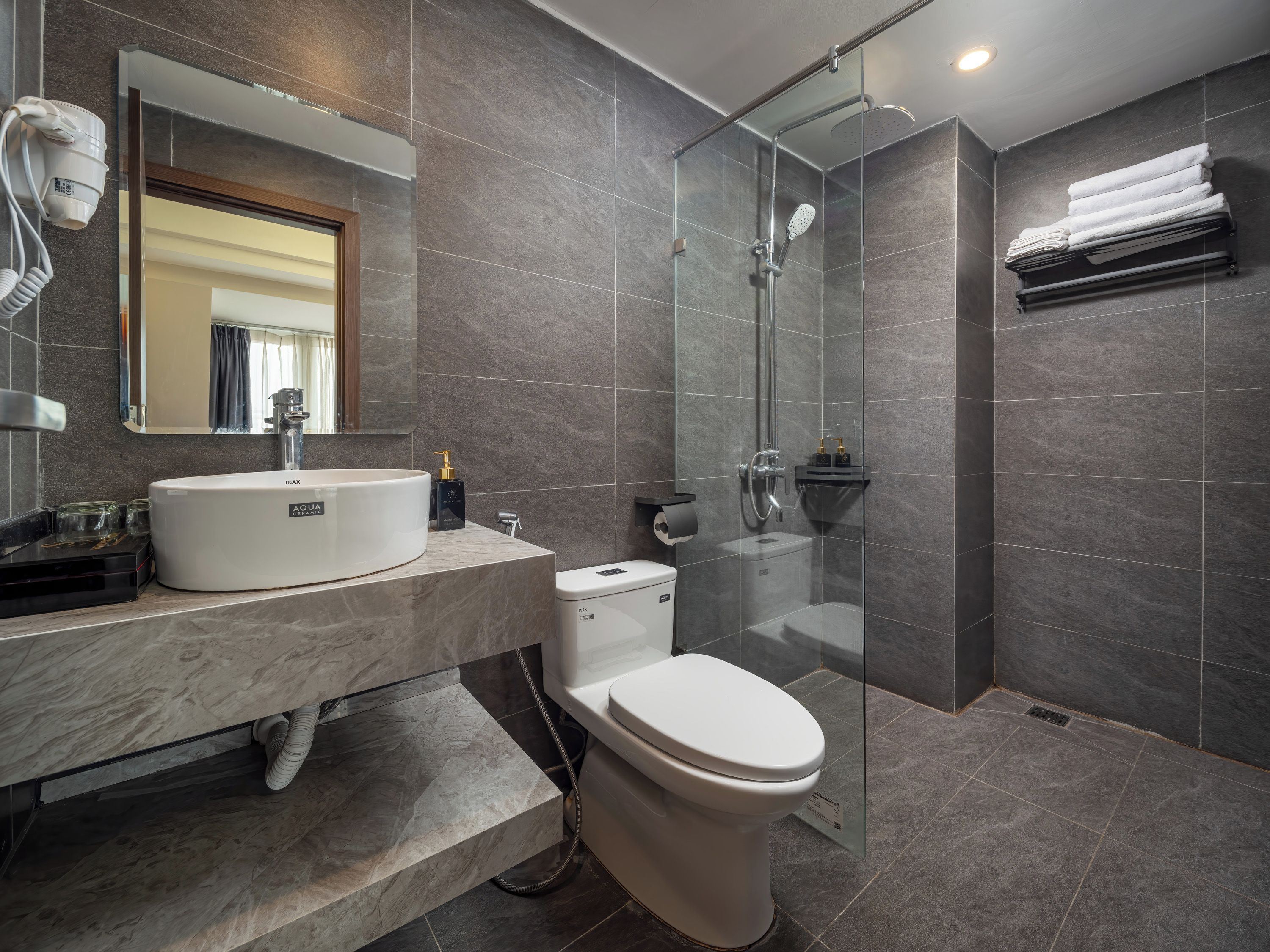 A modern bathroom with a glass-enclosed shower, a white sink, and a toilet.