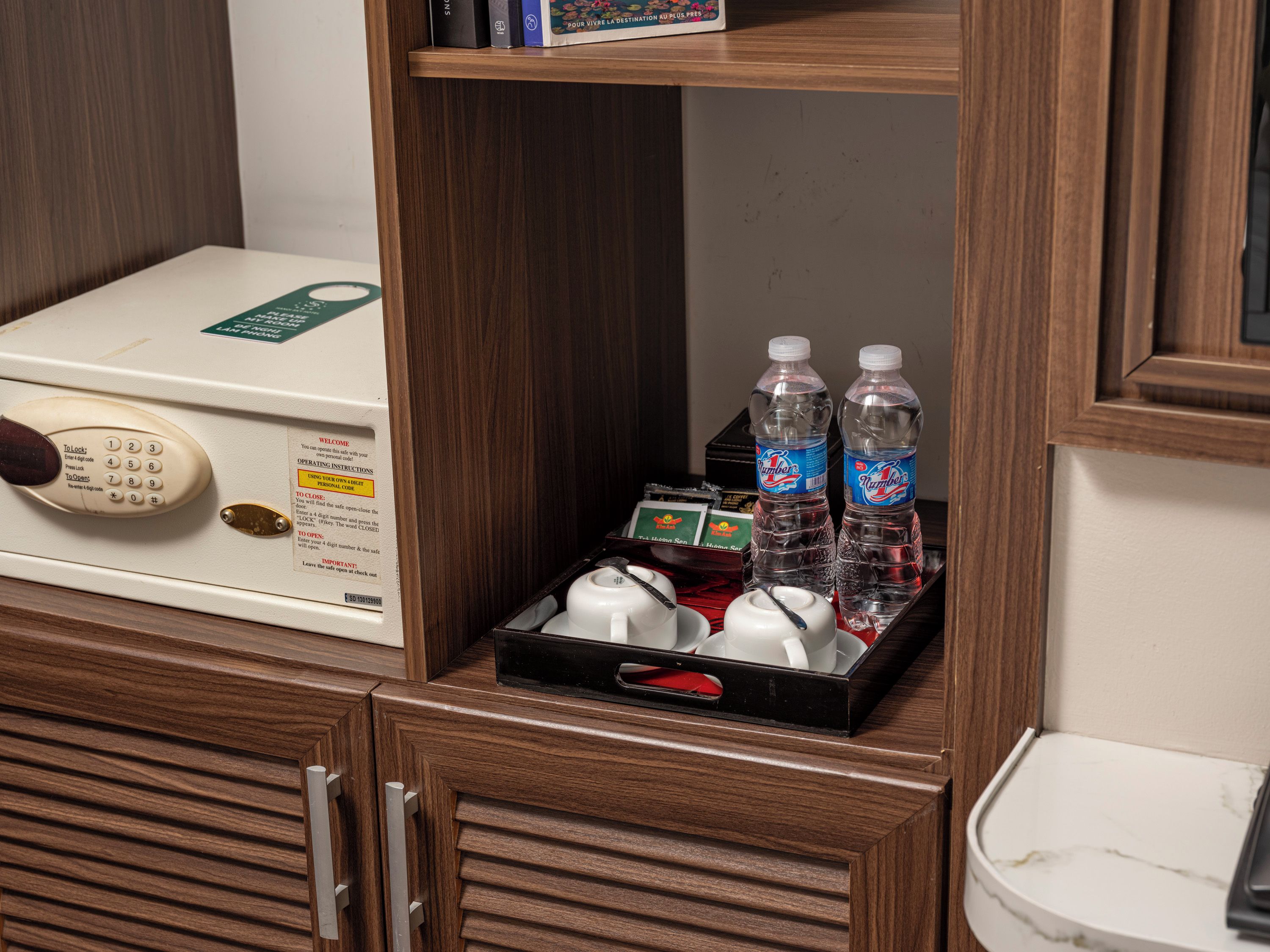 A hotel room with a minibar, a telephone, and a tray with bottles and cups.